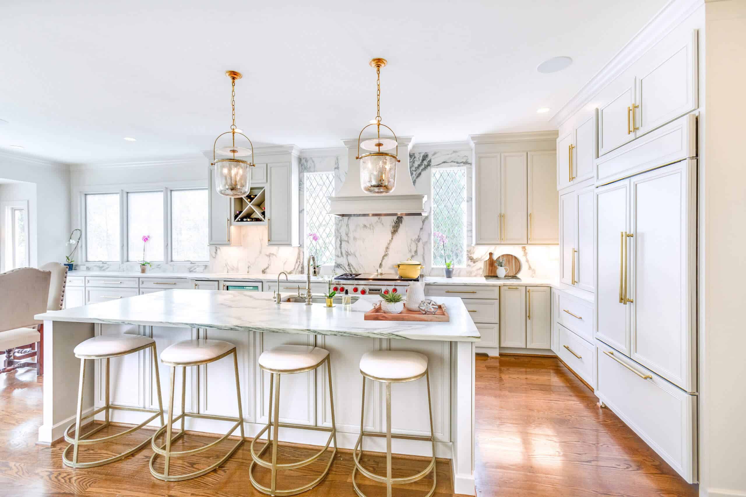 white kitchen with gold pull handles on cabinets with a large center island and bar seating