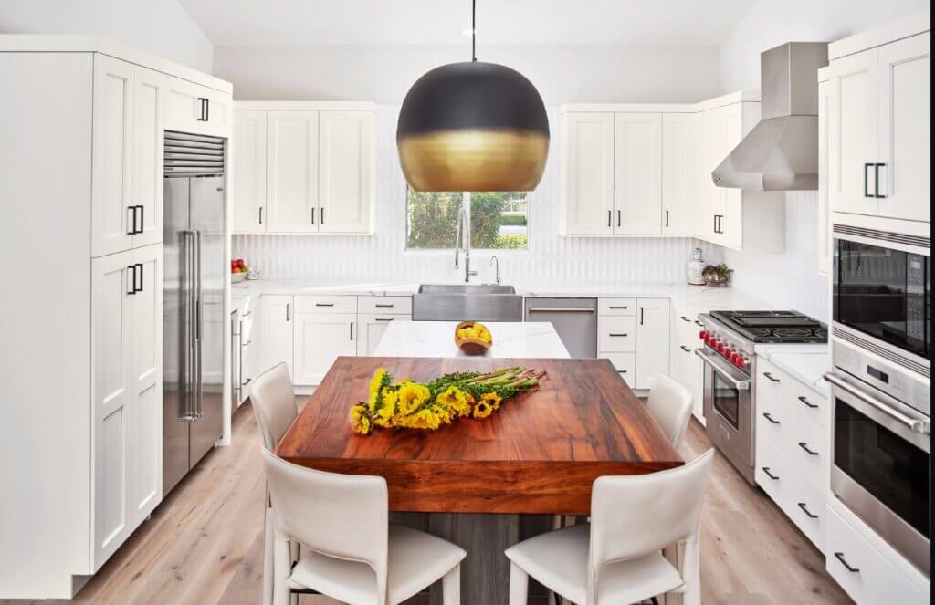 white kitchen cabinets with black hardware and wood island